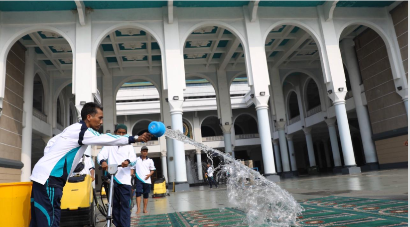 Petugas Masjid Nasional Al Akbar Surabaya, tengah membersihkan sajadah di dalam masjid. (Foto: Andhi Dwi/Ngopibareng.id)