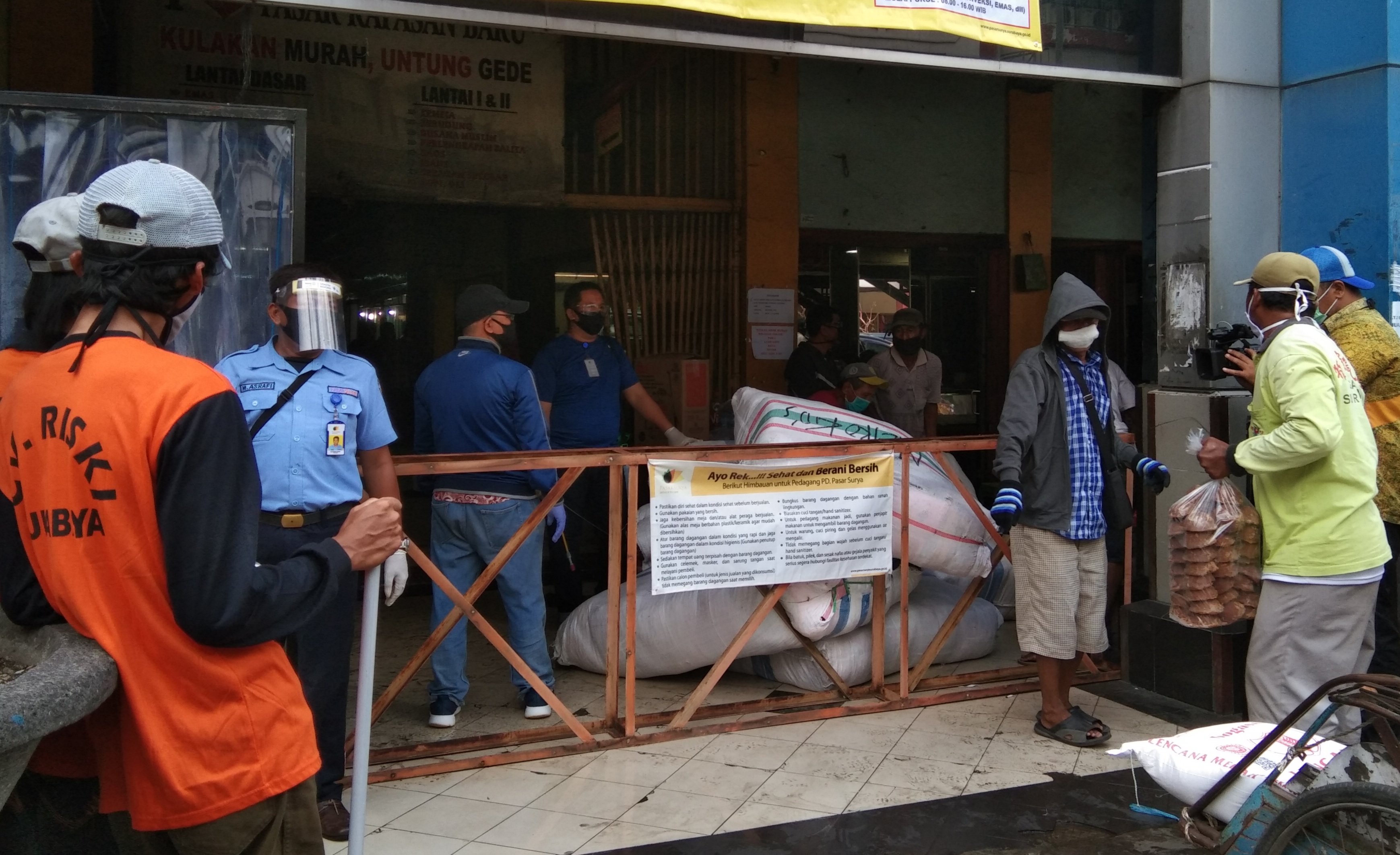 Beberapa pedagang harus diseprot desinfektan saat akan masuk Pasar Kapasan. (Foto: Ni'am Kurniawan/Ngopibareng.id)