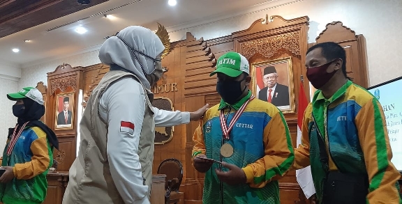 Gubernur Jatim, Khofifah Indar Parawansa memberikan bonus kepada salah satu peraih medali Peparpenas IX 2019 di Gedung Negara Grahadi, Surabaya, Sabtu 18 April 2020. (Faris Yarbo/Ngopibareng.id)