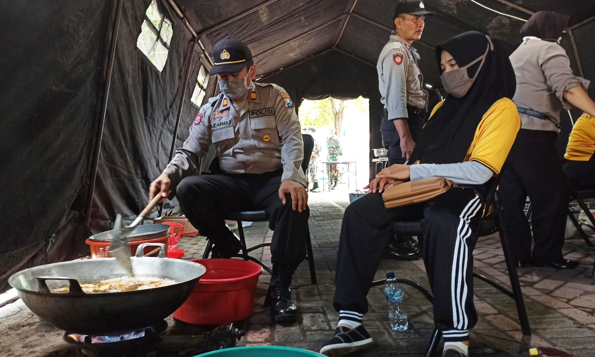 Anggota Polri sedang memasak di dapur umum TNI-Polri yang ada di Taman Bkambangan, Banyuwangi (foto: Hujaini/ngopibareng.id)