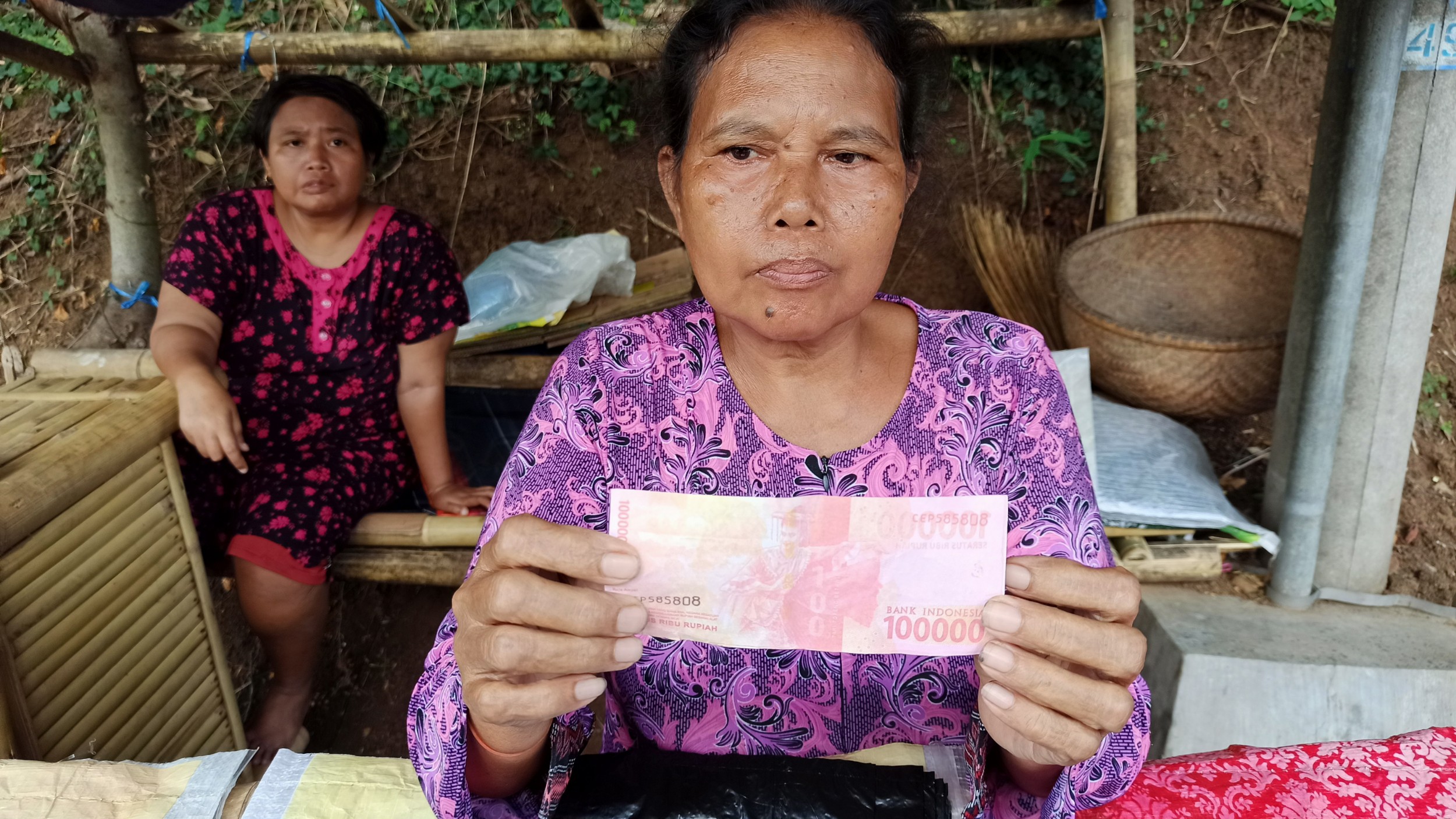 Aisyah menunjukkan uang yang diduga palsu (foto: Hujaini/ngopibareng.id)