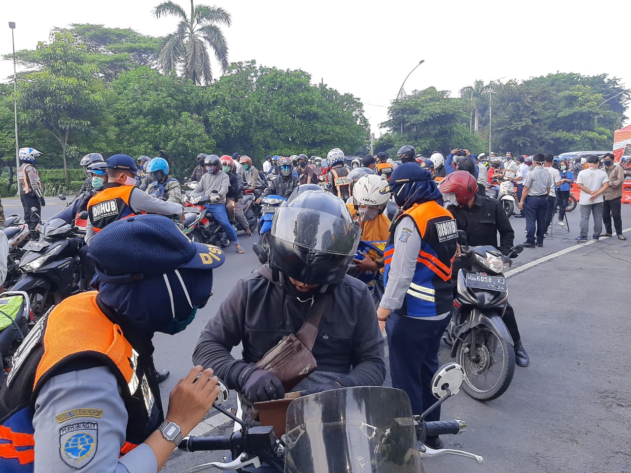 Petugas dari Dinas Perhubungan Kota Surabaya melakukan pemeriksaan terkait kedatangan pengendara motor dari arah Sidoarjo ke Surabaya. (Foto: Pita Sari/Ngopibareng.id)