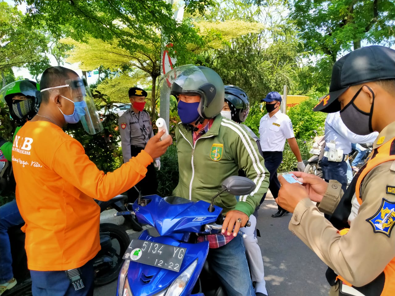 Petugas dari Pemkot Surabaya memeriksa pengendara yang hendak melewati cek poin Bundaran Waru, Surabaya. (Foto: Fariz Yarbo/Ngopibareng.id)