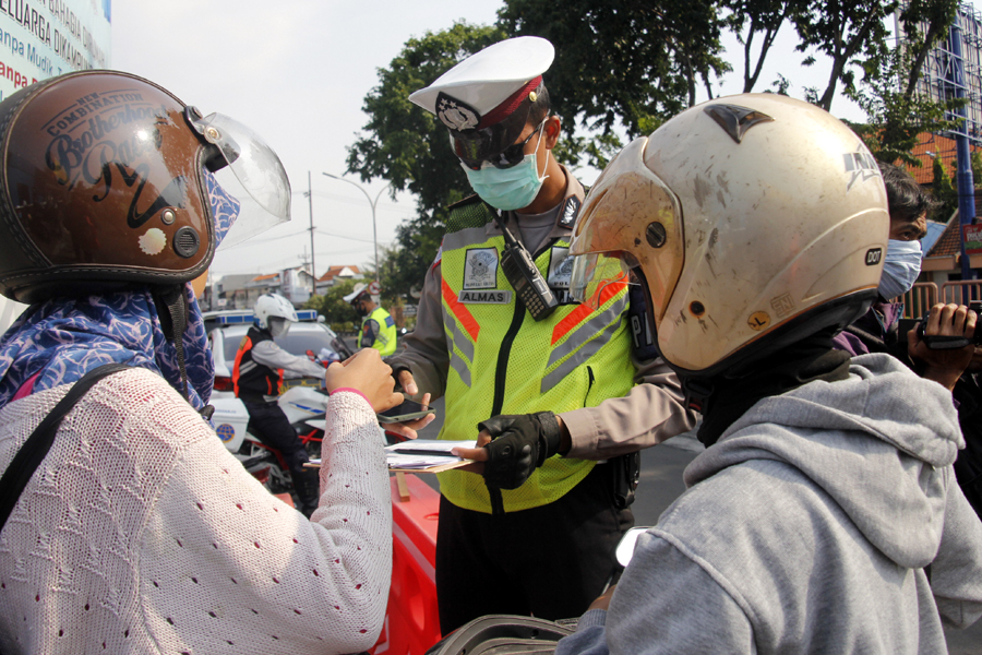 Petugas menindak pengendara yang melakukan pelanggaran di check point Waru, Sidoarjo, Jawa Timur, pada Sabtu 2 April 2020 sore. (Foto: Fariz Yarbo/Ngopibareng.id)