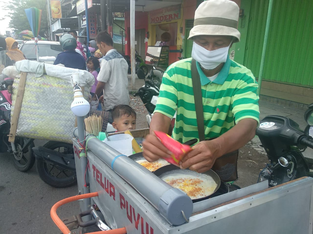Pedagang jajanan anak Papeda Telur, Sugiman, memakai masker sesuai protokol kesehatan saat pandemi corona kawasan Pasar Cukir, Jombang, Jawa Timur. (Foto: M. Rizqi/Ngopibareng.id)