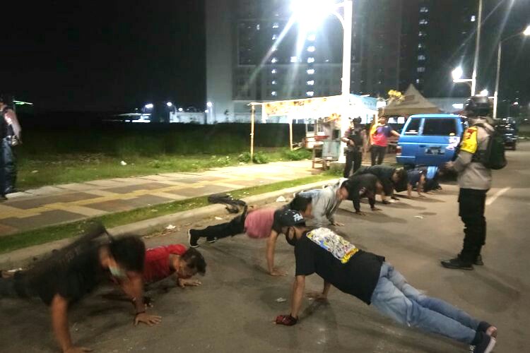 Hukuman push-up kepada warga yang masih nekat berkumpul dalam jumlah banyak saat malam hari. (Foto: Dok. Humas Polres Jakarta Barat)