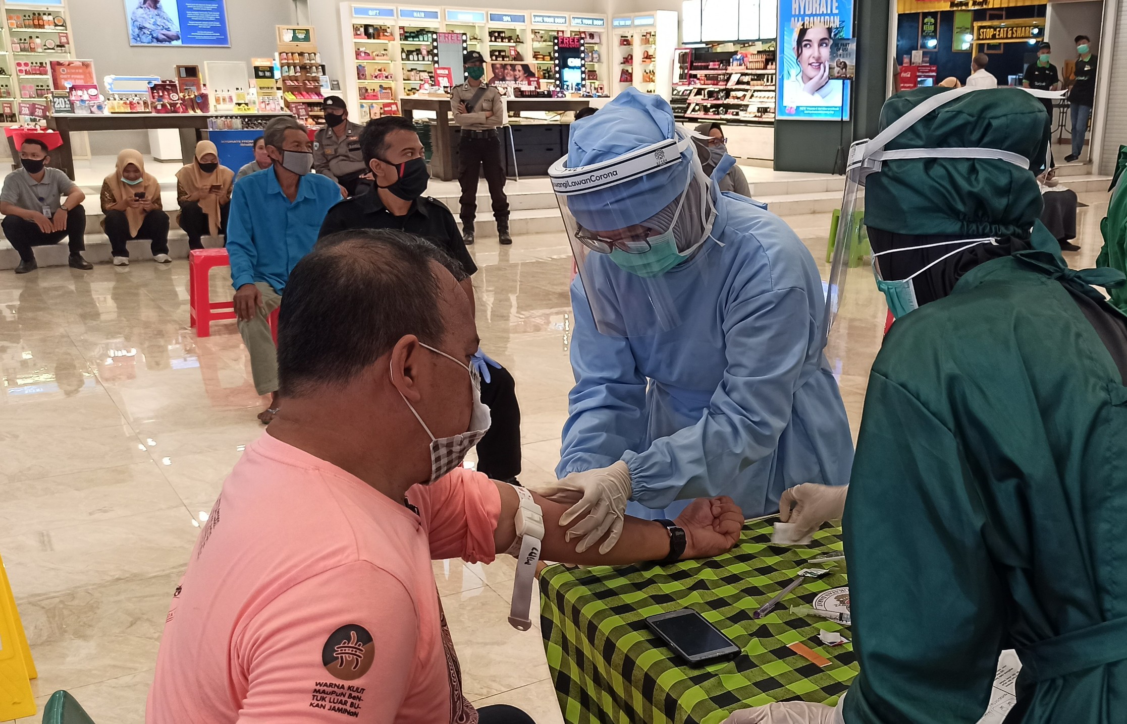 Seorang pengunjung salah satu pusat perbelanjaan di Kota Banyuwangi sedang diambil sampel darahnya untuk dilakukan rapid test (foto: Hujaini/ngopibareng.id)