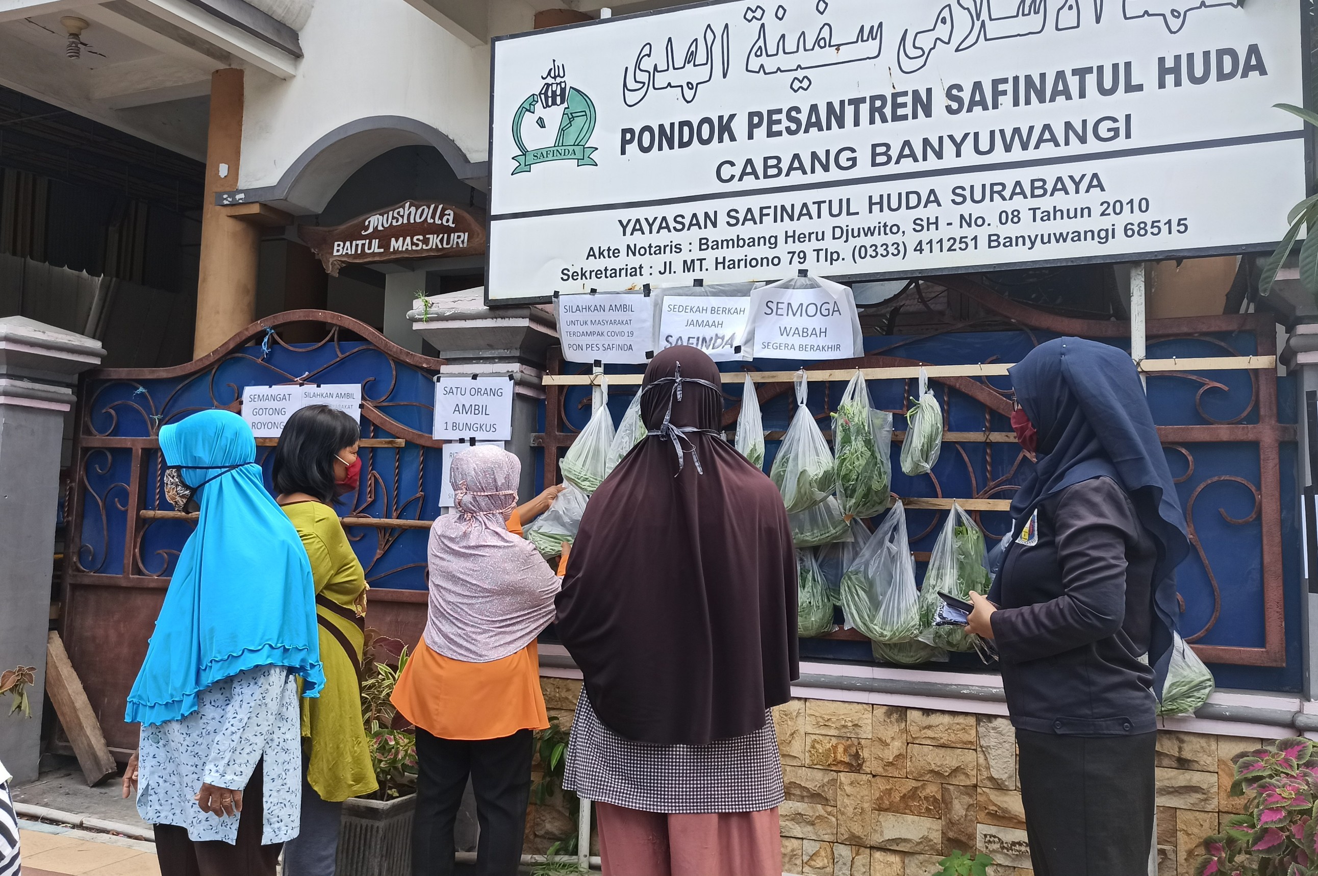 Sejumlah warga mengambil bahan makanan dan sayuran dari gantungan yang disediakan pondok pesantren Safinda (foto : Hujaini/ngopibareng.id)