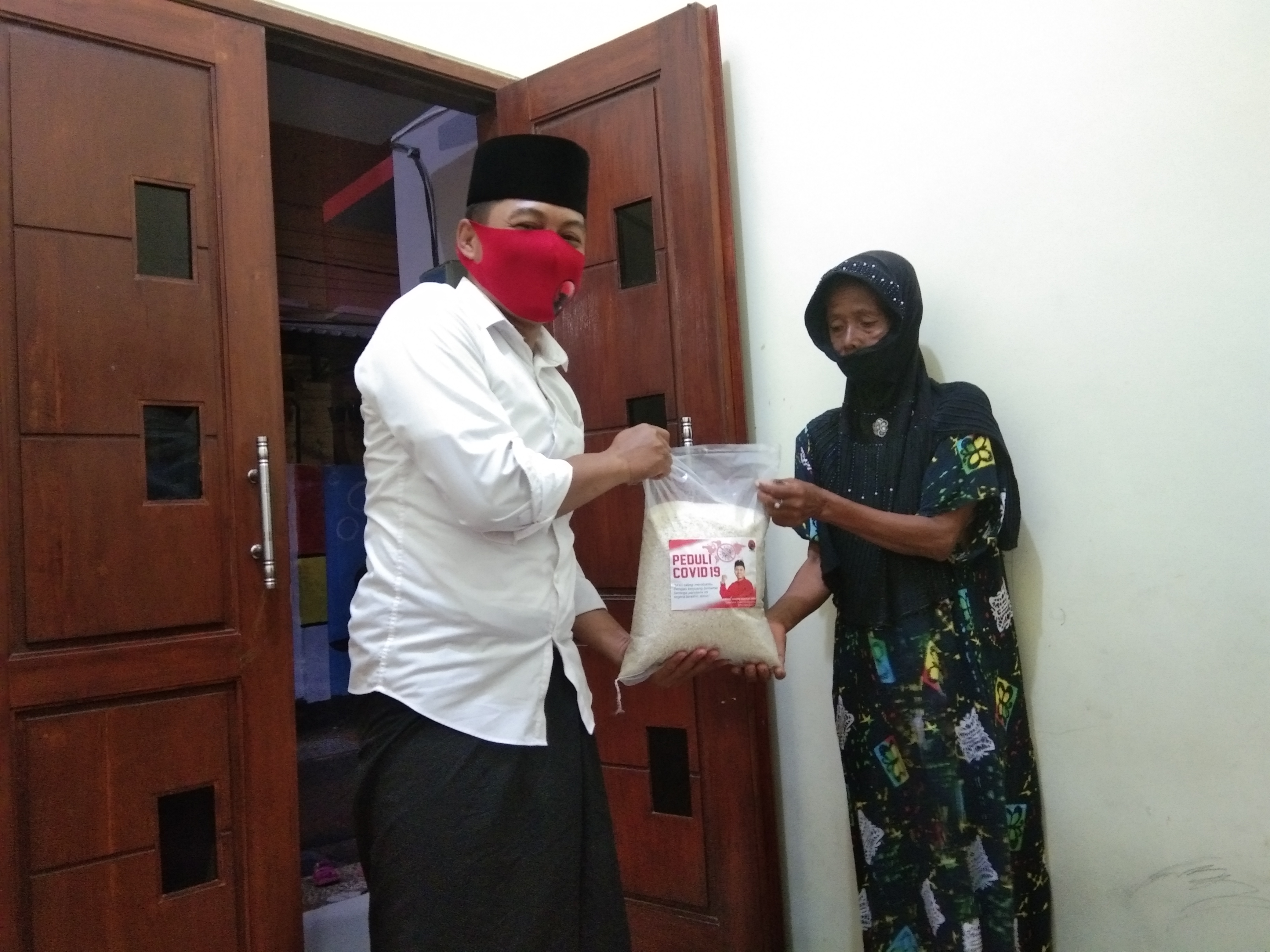 Abdul Ghoni Mukhkas Ni'am saat membagikan beras kepada salah satu warga Kenjeran Kecamatan Bulak Surabaya. (Foto: Ni'am Kurniawan/Ngopibareng.id)