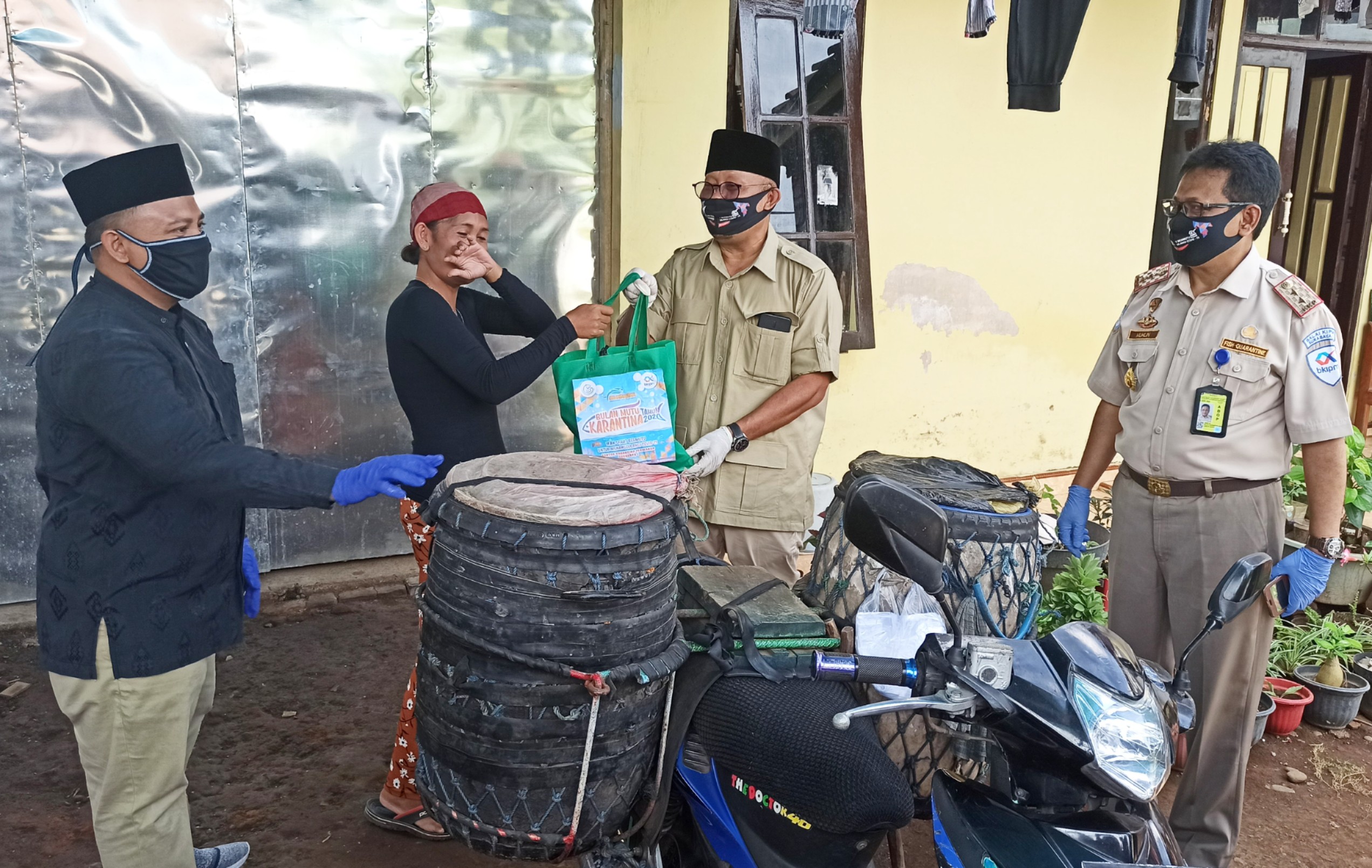 Anggota Komisi IV DPR RI Sumail Abdullah bersama Kepala BKIPM Surabaya I Muhlin menyerahkan bantuan ikan segar dan olahan ikan pada masyarakat (foto: Hujaini/ngopibareng.id)