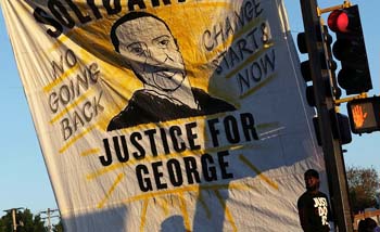 Sebuah spanduk dengan gambar George Floyd dipasang pengunjuk rasa di persimpangan jalan di  Kota Minneapolis, di Minneapolis, Minnesota [Foto: Reuters)