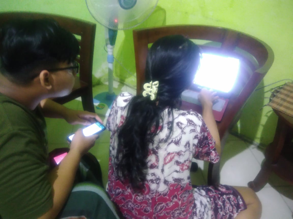 Seorang ibu di Surabaya, Mariska Safitri  bersama putranya Rama, sedang mencoba PPDB  sistem online. (Foto: Asmanu/Ngopibareng.id)