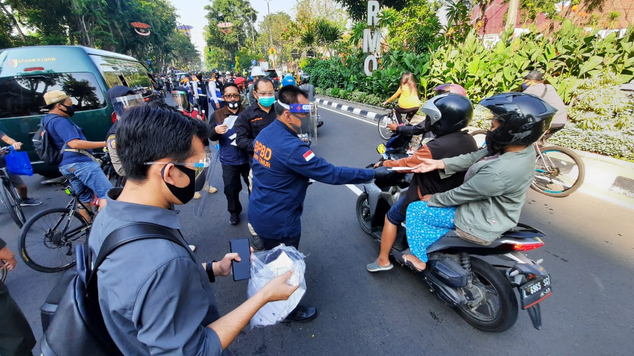 Sekdaprov Jatim, Heru Tjahjono membagikan masker kepada pengendara di kawasan Taman Bungkul, Surabaya, Minggu 28 Juni 2020. (Fariz Yarbo/Ngopibareng.id)
