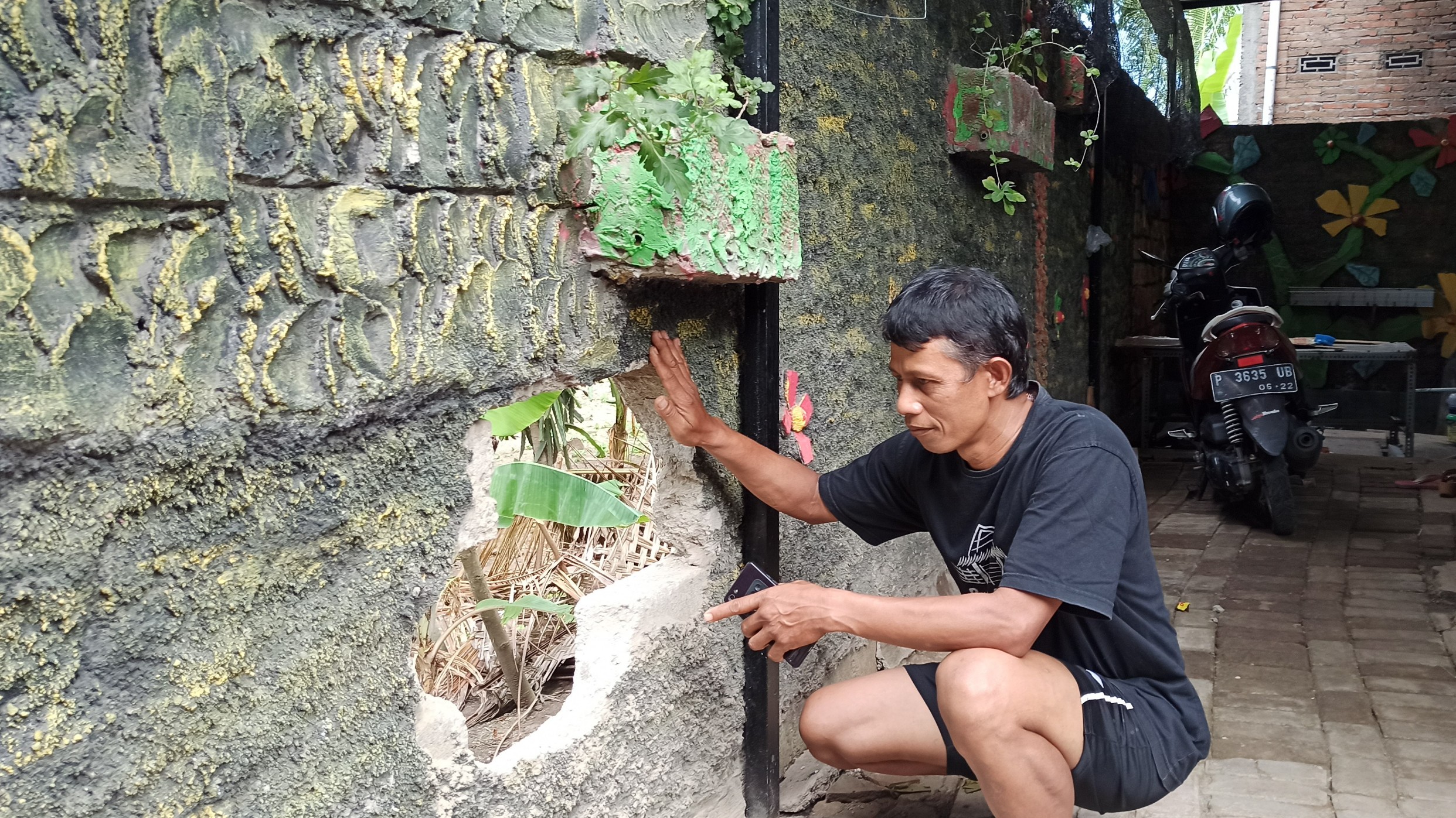 Saperan menunjukkan lubang pada tembok rumahnya (foto: Hujaini/Ngopibareng.id)