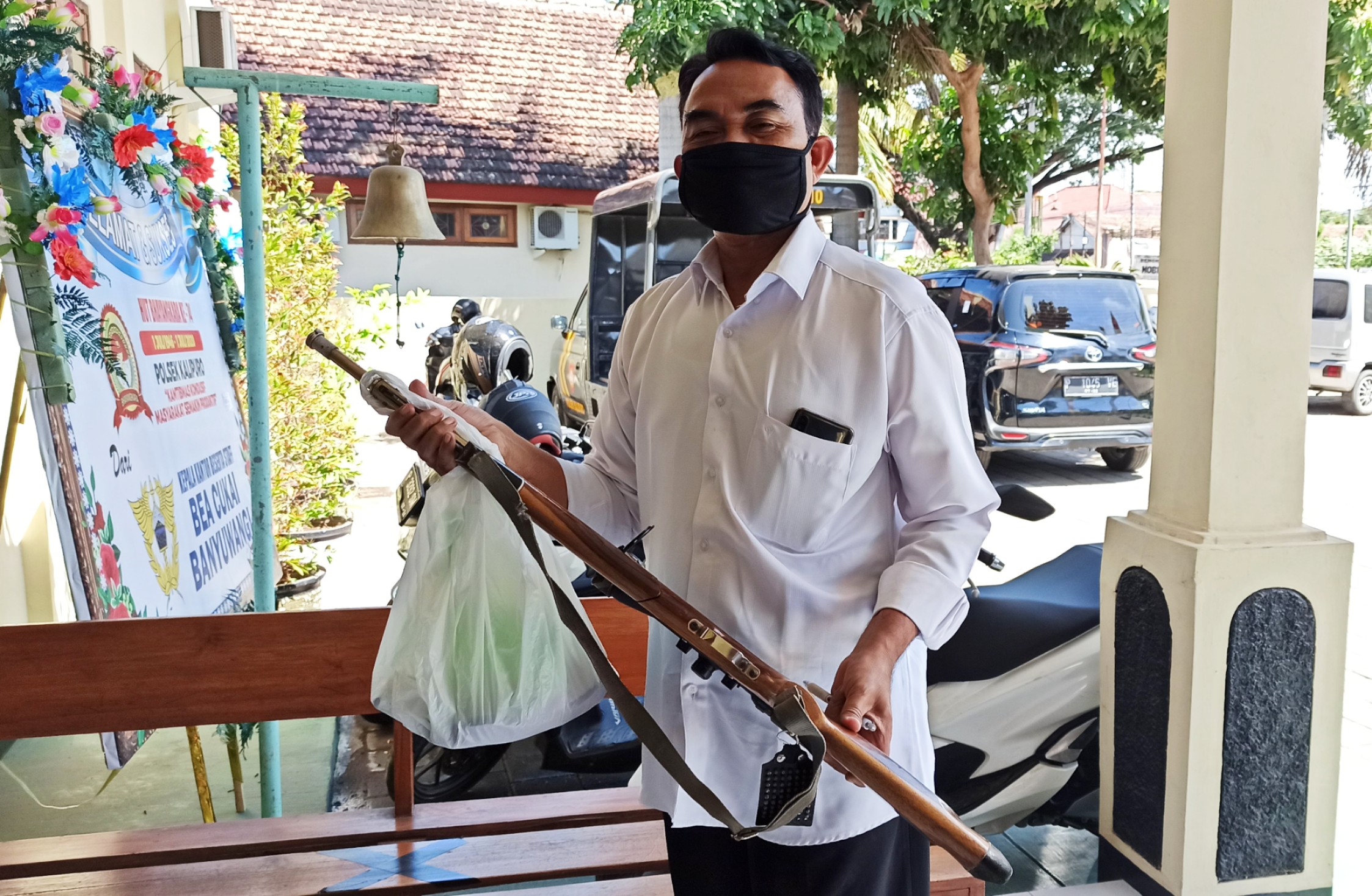Kanit Reskrim Polsek Kalipuro Ipda Suyono menunjukkan senapan angin yang disita dari rumah korban. (Foto: Muh Hujaini/Ngopibareng.id)