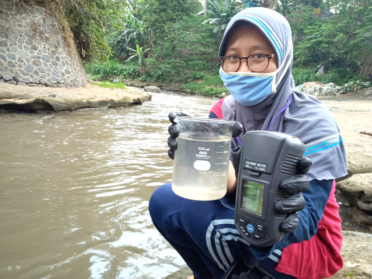 Peneliti Ecoton, Eka Clara Budiarti saat mengambil sampel air di Sungai Brantas Malang (Foto: Lalu Theo/ngopibareng.id)