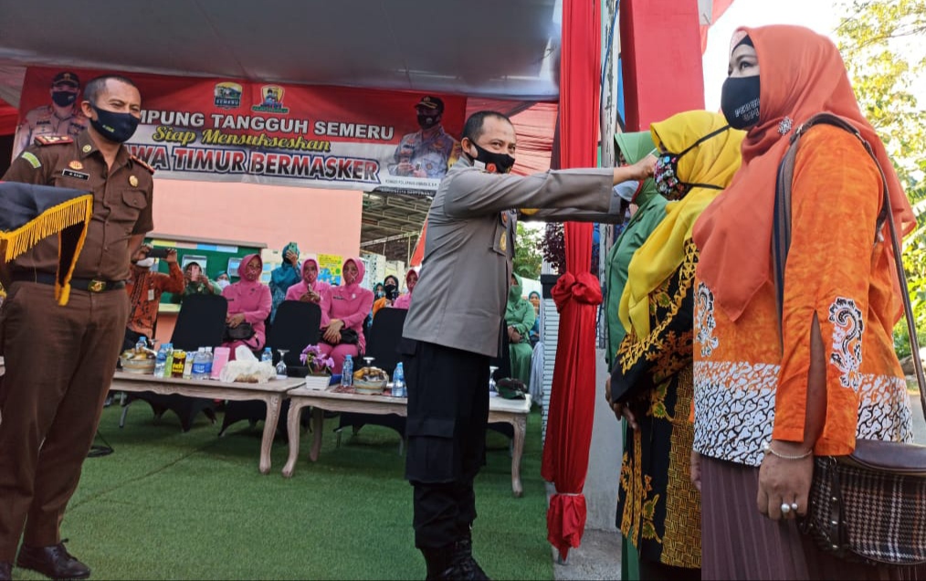 Kapolresta Banyuwangi Kombespol Arman Asmara Syarifuddin memasangkan masker pada perwakilan warga. (Foto: Muh Hujaini/Ngopibareng.id)