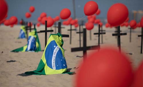 Pasir Pantai Copacabana di Rio de Janeiro yang terkenal dipenuhi salib, balon merah dan  bendera Brazil  untuk menghormati para  korban COVID-19 yang terus berjatuhan. (Foto:AP)