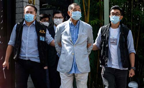Polisi China membawa bos media Hong Kong, Jimmy Lai (tengah), dengan diborgol ke luar dari rumahnya di Hong Kong. (Foto: AP)