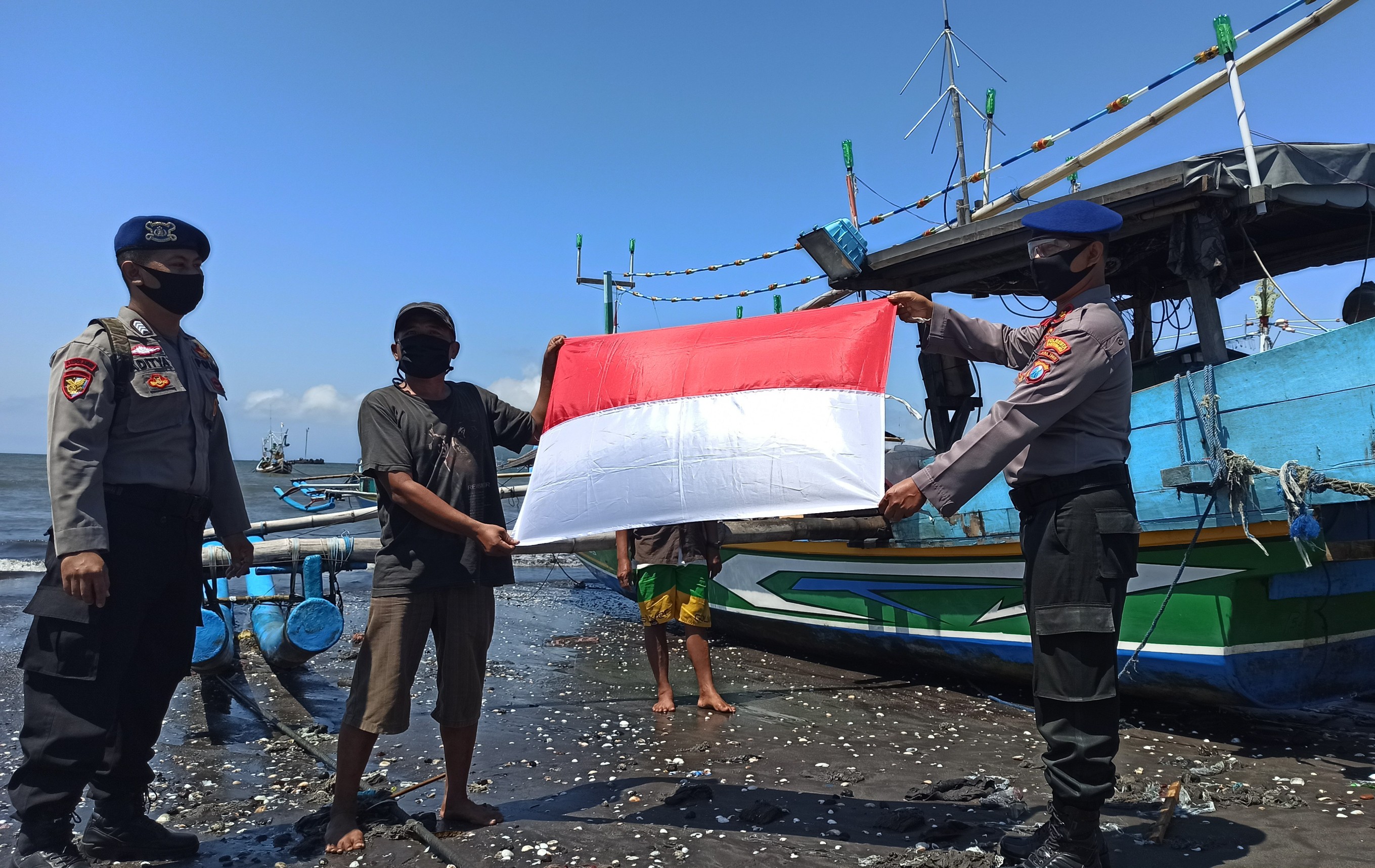 Kasat Polairud Polresta Banyuwangi, Kompol Sudarsono menyerahkan bendera kepada nelayan Muncar. (Foto: Muh Hujaini/Ngopibareng.id)