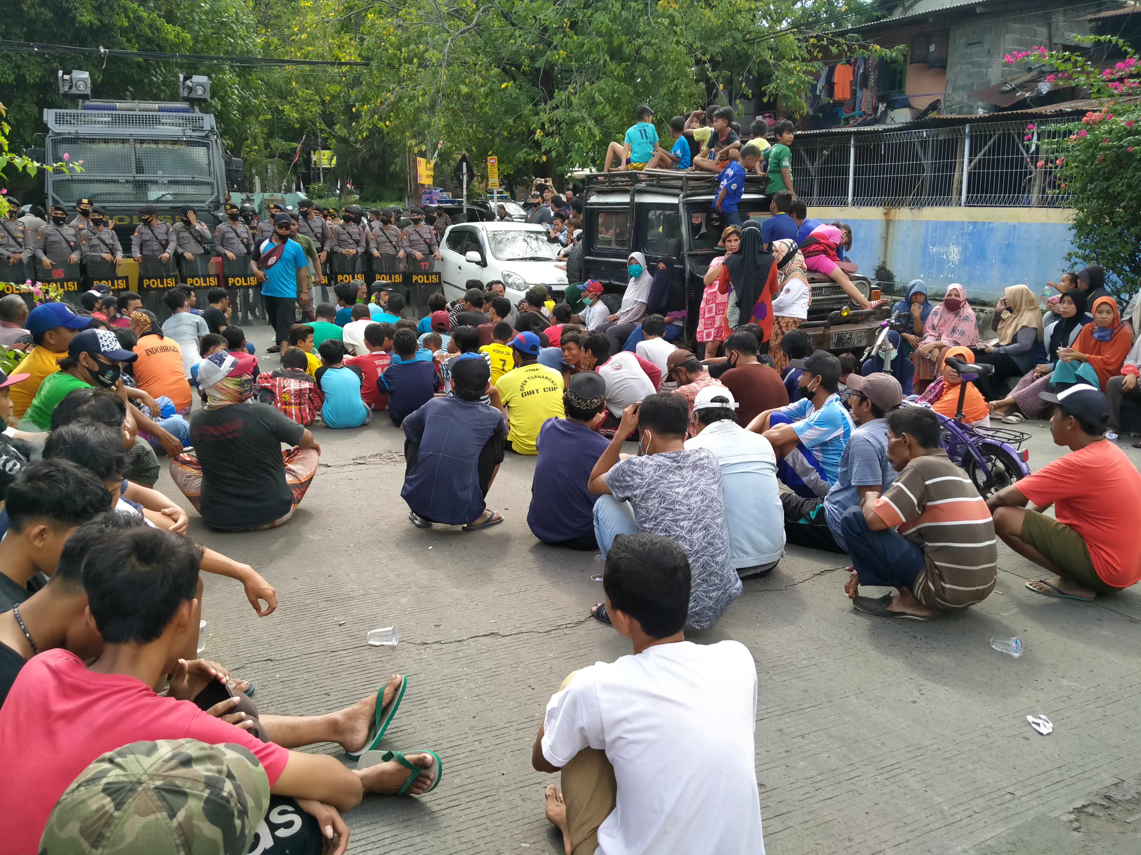 Puluhan warga saat menunggu rekannya yang sempat diamankan di Mapolres Gresik. (foto: Azharil Farich/Ngopibareng.id)