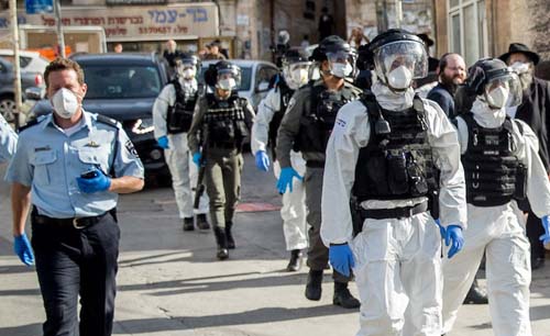Ilustrasi polisi Israel berpratoli dengan APD lengkap sebelum Israel memberlakukan lockdown minggu depan. (Foto: JTA)