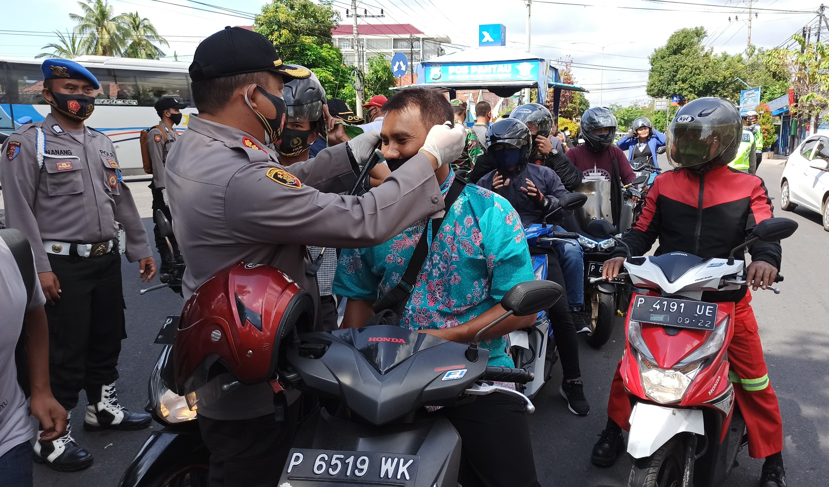 Kapolresta Banyuwangi Kombespol Arman Asmara Syarifuddin memasangkan masker pada pengendara motor. (Foto: Muh Hujaini/Ngopibareng.id)