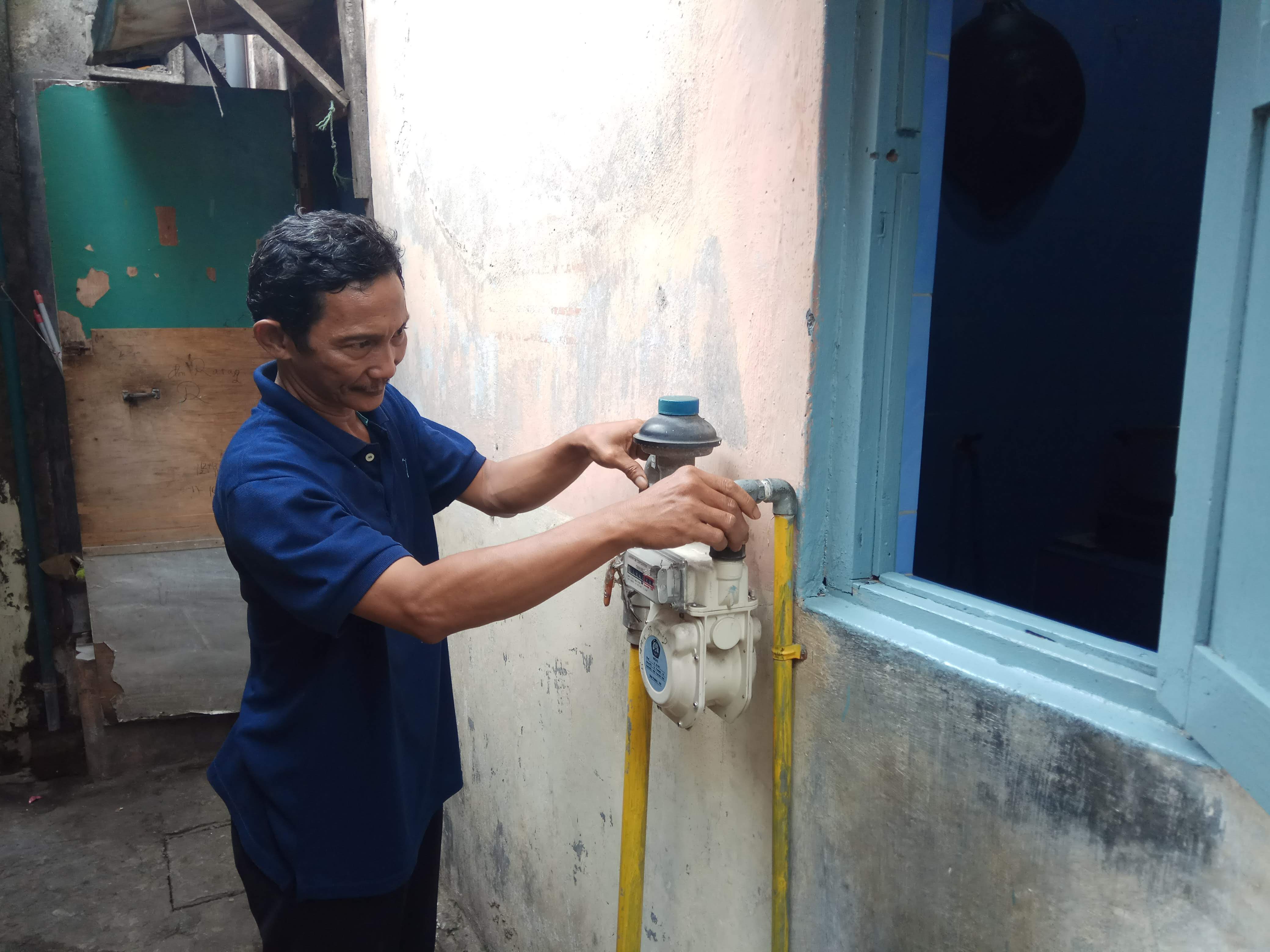 Saroni menunjukkan meteran gas PGN di rumahnya di sekitar Keputran Panjunan. Dengan Jargas PGN dia bisa berkontribusi dalam program permakanan untuk lansia di Surabaya. (Foto: Amir Tejo/Ngopibareng.id)
