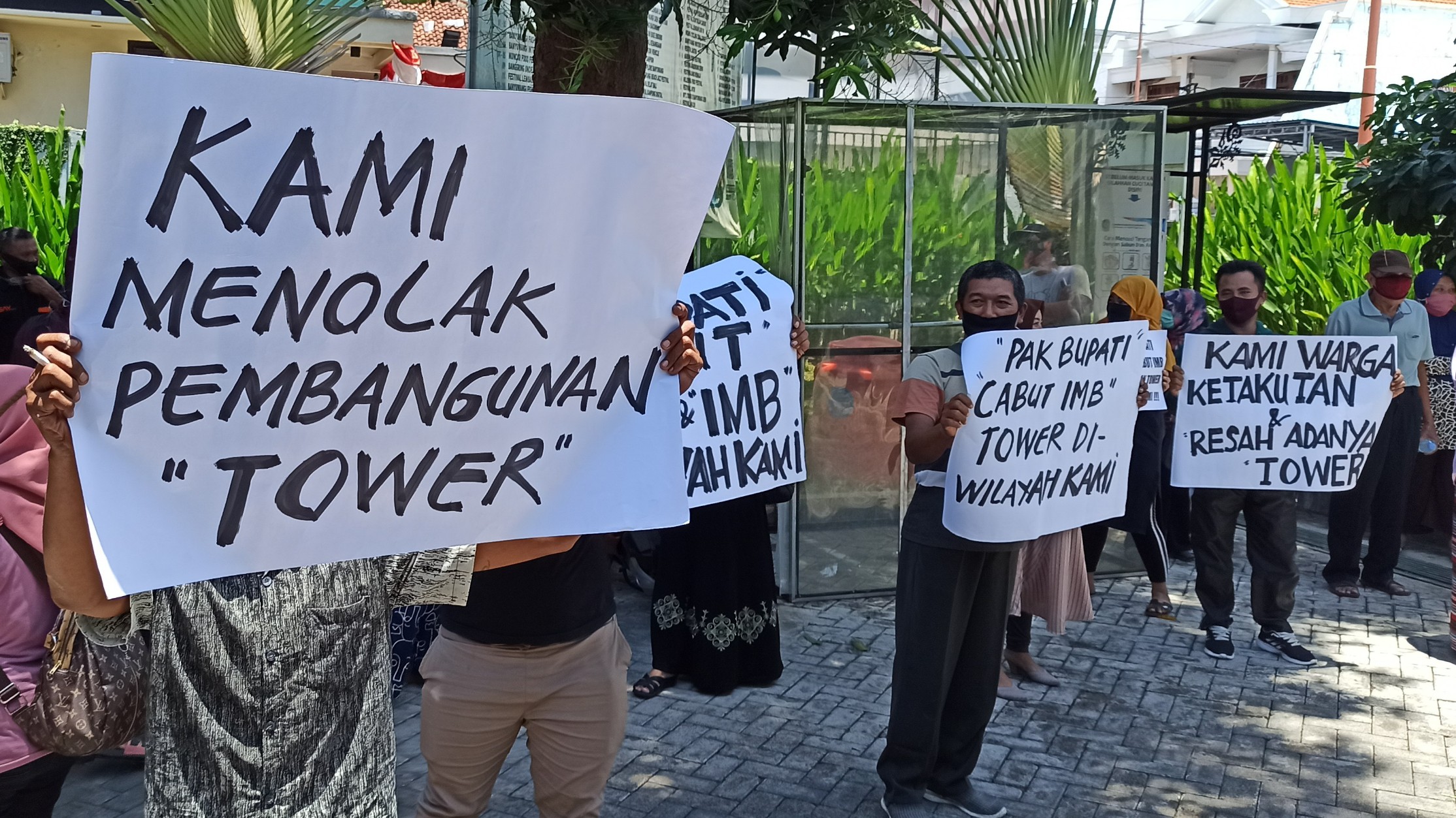 Warga membentangkan poster penolakan pendirian tower di kantor DPMPTSP Banyuwangi (foto: Muh Hujaini/Ngopibareng.id)