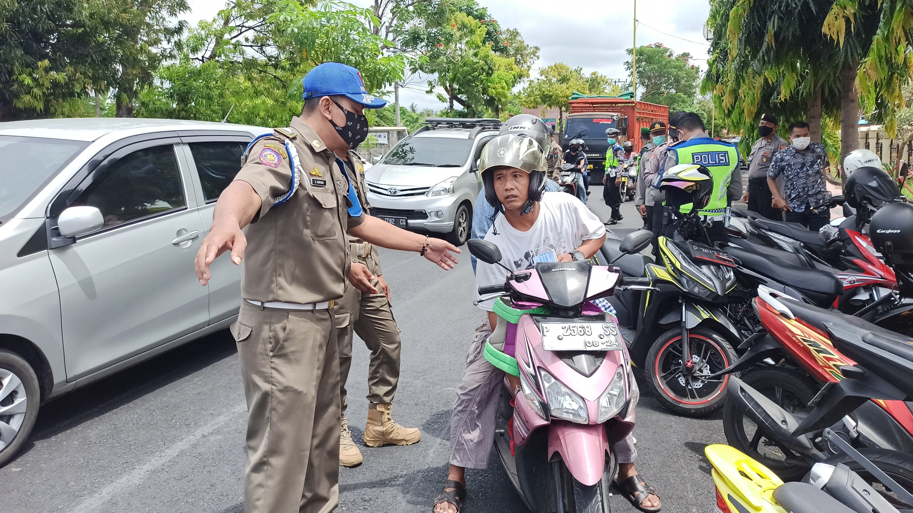 Petugas menghentikan salah seorang pengguna jalan yang tidak mengenakan masker. (Foto: Muh. Hujaini/Ngopibareng.id) 