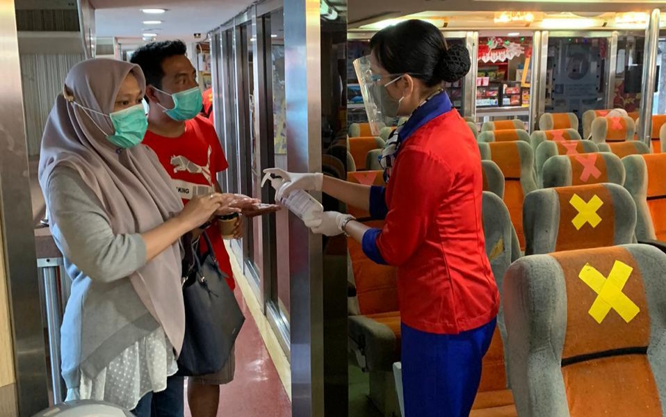 Kru kapal menyemprotkan hand sanitizer pada penumpang  kapal penyeberangan Ketapang-Gilimanuk. (Foto: Muh Hujaini/Ngopibareng.id)
