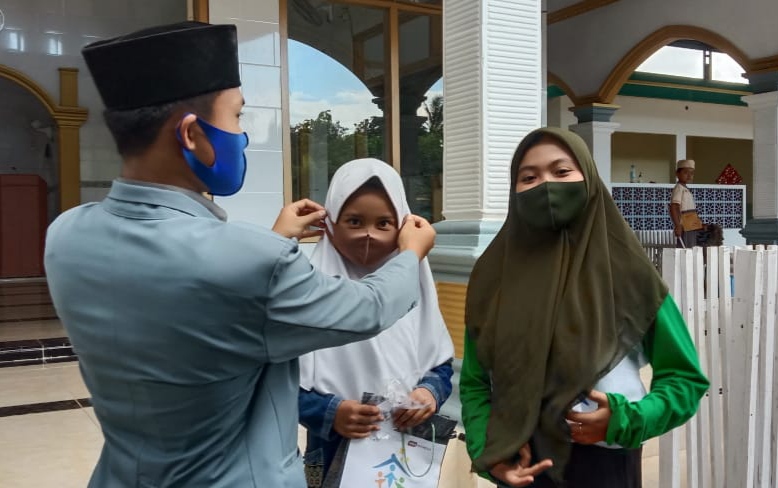 Komunitas Keluarga Cemerlang memasangkan masker pada  anak di salah satu TPQ  di wilayah Kecamatan Muncar, Banyuwangi. (Foto: Istimewa)
