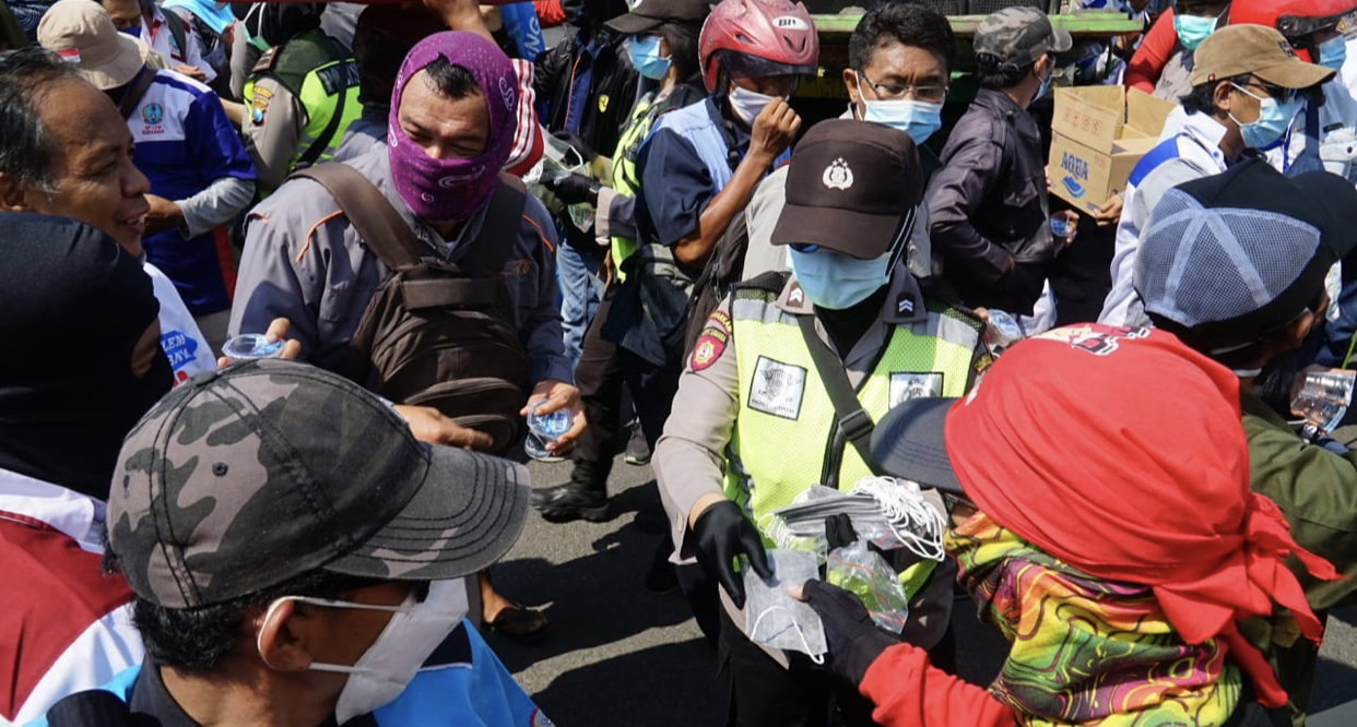 Aparat Kepolisian membagikan masker gratis saat demo tolak Omnibus Law di Gedung DPRD Jatim, pada Kamis, 22 Oktober 2020. (Foto: Humas Polrestabes Surabaya)