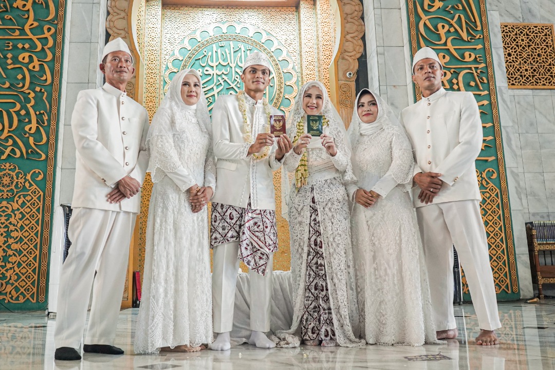 Rachmat Irianto dan Siti Qonita menunjukkan surat nikahnya didampingi kedua orang tua mereka. (Foto: persebaya.id)