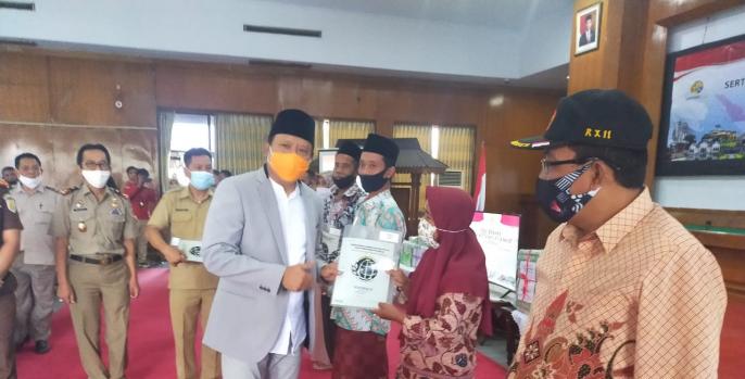 Bupati Pasuruan menyerahkan sertifikat tanah kepada warga penerima. 