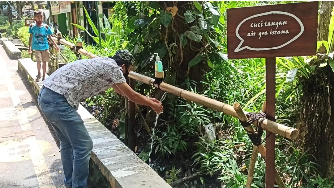 Salah seorang pengunjung Taman Nasional Alas Purwo (TNAP) mencuci tangan di pancuran yang berada di pintu masuk lokasi wisata. (Foto: Muh Hujaini/Ngopibareng.id)