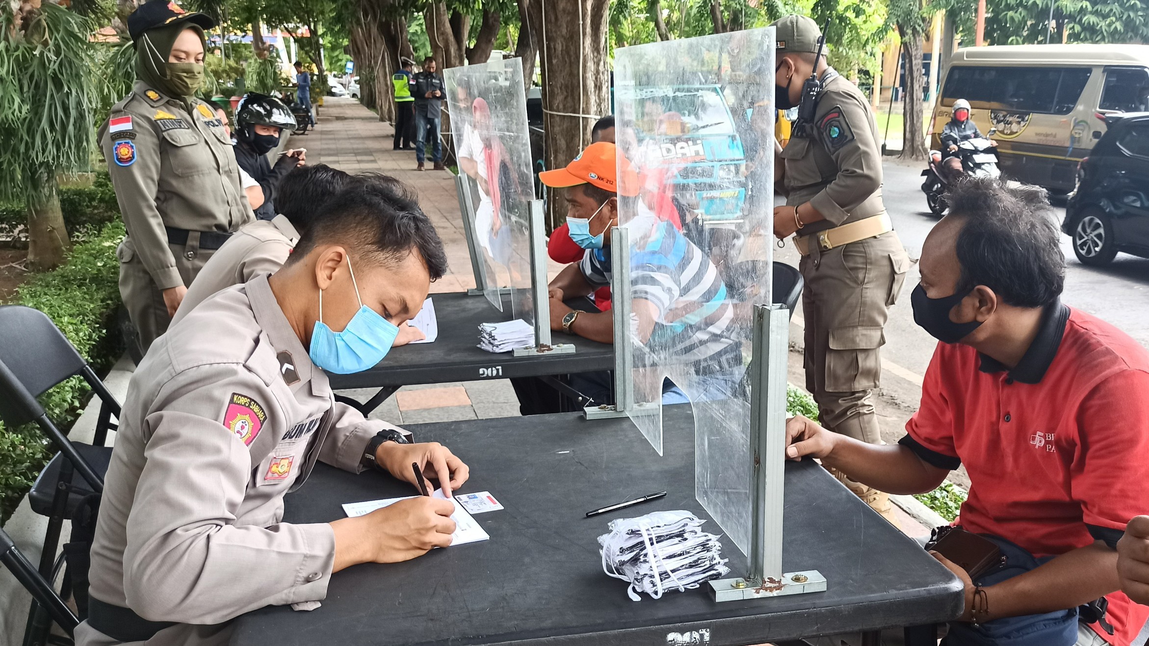 Petugas memberikan sanksi pada pengendara yang tidak menggunakan masker. (Foto: Muh. Hujaini/Ngopibareng.id)
