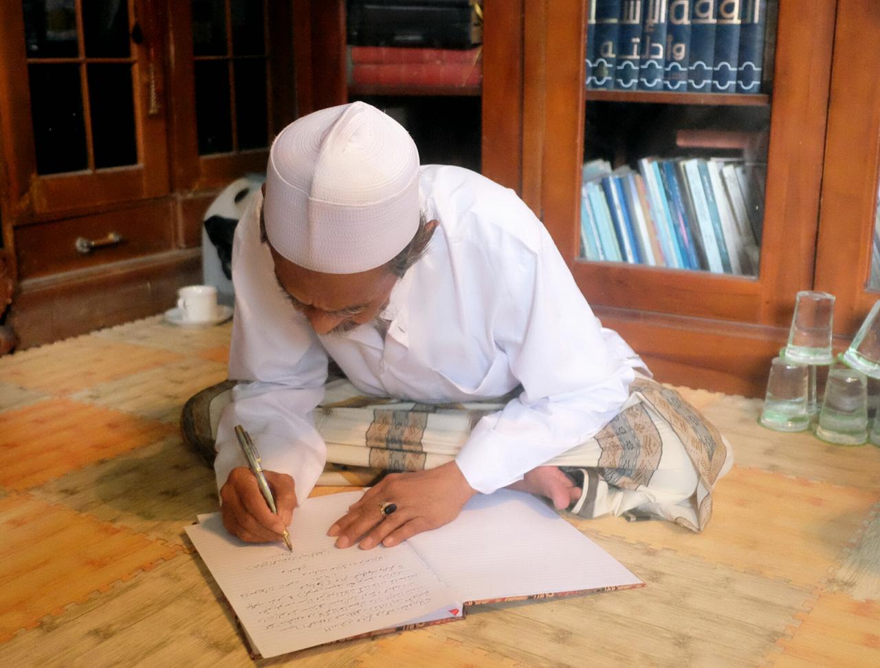 Pengasuh Pesantren Sidogiri KH Nawawi Abdul Djalil saat menulis maklumat coblos Saifullah Yusuf (Gus Ipul)-Adi Wibowo (Mas Adi). (Foto: Istimewa)