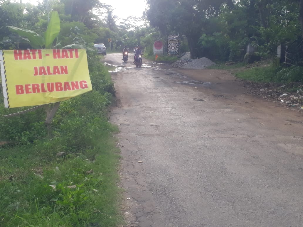 Akses jalan desa antara Desa Kaligambar sampai Kalitengah menuju lokasi wisata Pantai Serang, Blitar, Jawa Timur, tampak rusak. (Foto: Choirul Anam/Ngopibareng.id)