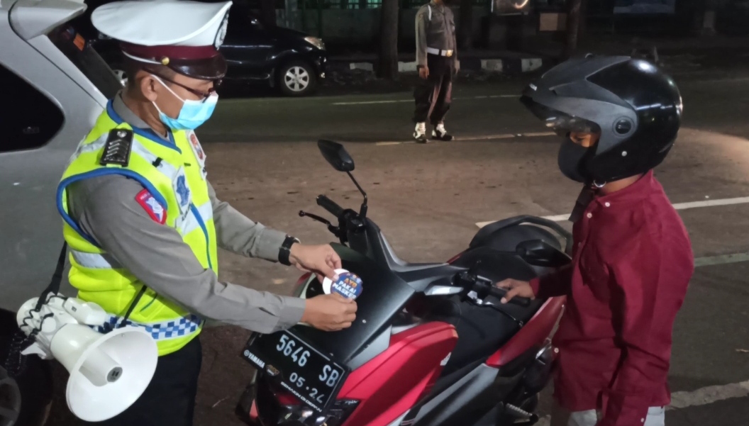 Petugas menempelkan stiker 'Ayo Pakai Masker' dalam Operasi Yustisi yang di gelar di Jl. A. Yani (foto:Muh Hujaini/Ngopibareng.id)