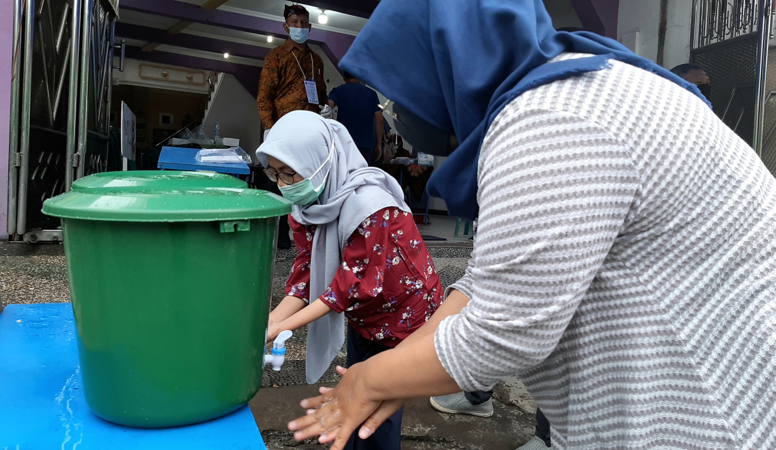 Warga saat mencuci tangan sebelum masuk TPS 056 alan Karang Asem, Surabaya. (Foto: Pita Sari/Ngopibareng.id)
