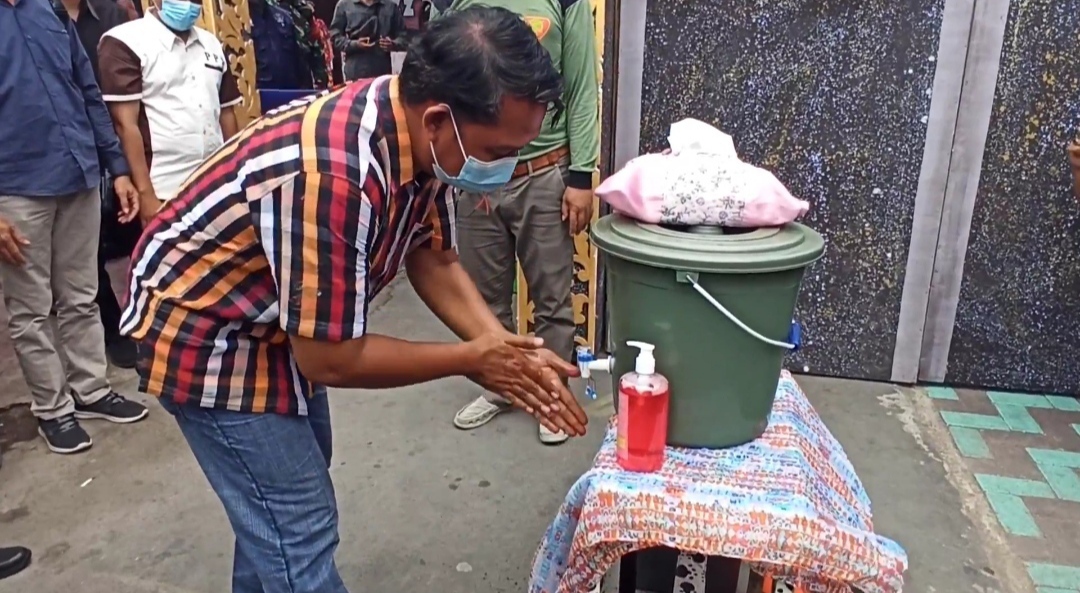 Salah seorang warga mencuci tangan sebelum masuk ke TPS (foto: Muh Hujaini/Ngopibareng.id)