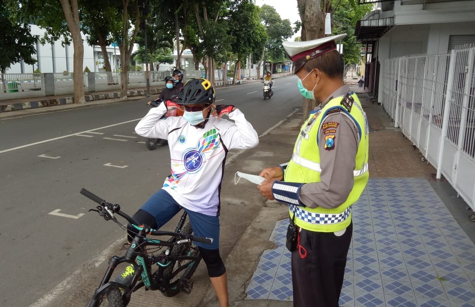 Seorang Polantas memberikan masker pada pengguna jalan yang tidak menggunakan masker. (Foto: Istimewa)