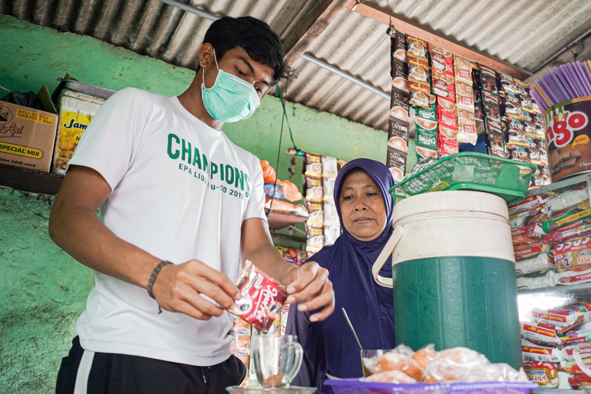 Andhika Ramadhani ketika turut membantu ibunya menjaga warung kopi sang Ibu. (Foto: Persebaya.id)