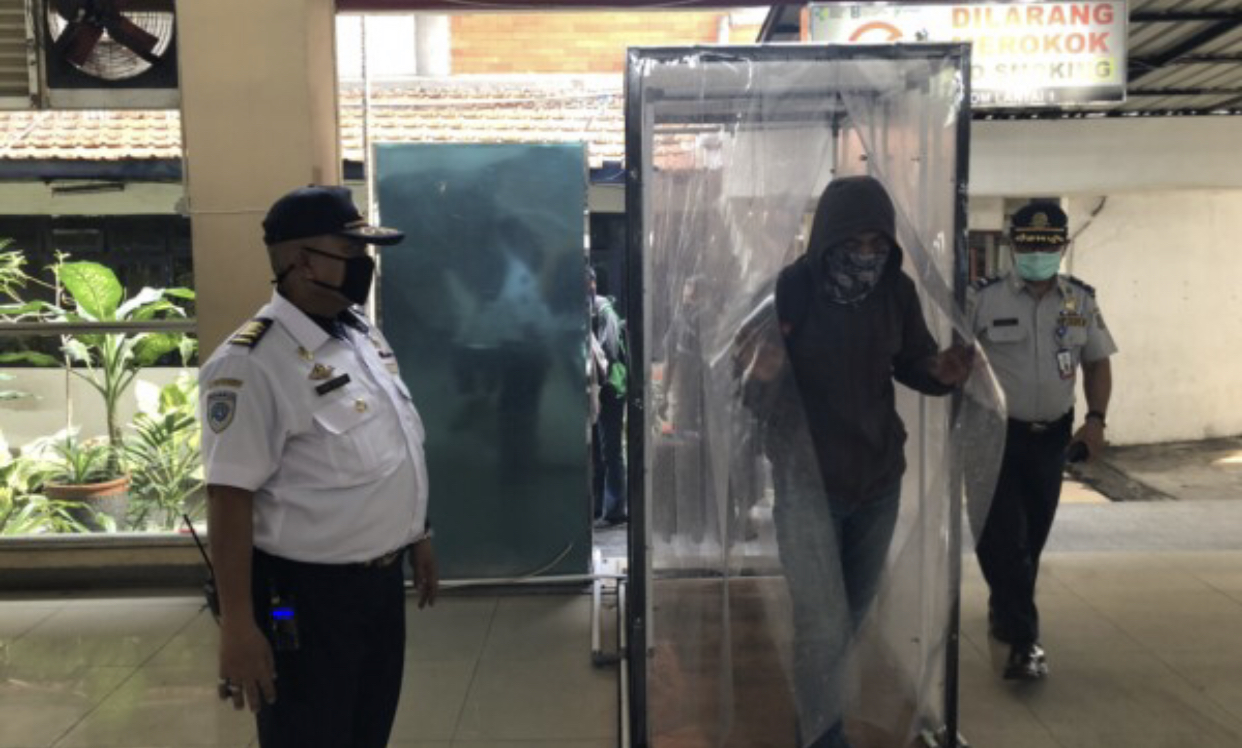Imam Hidayat, tengah memantau penumpang yang memasuki bilik sterilisasi di Terminal Purabaya (Andhi Dwi/Ngopibareng.id)