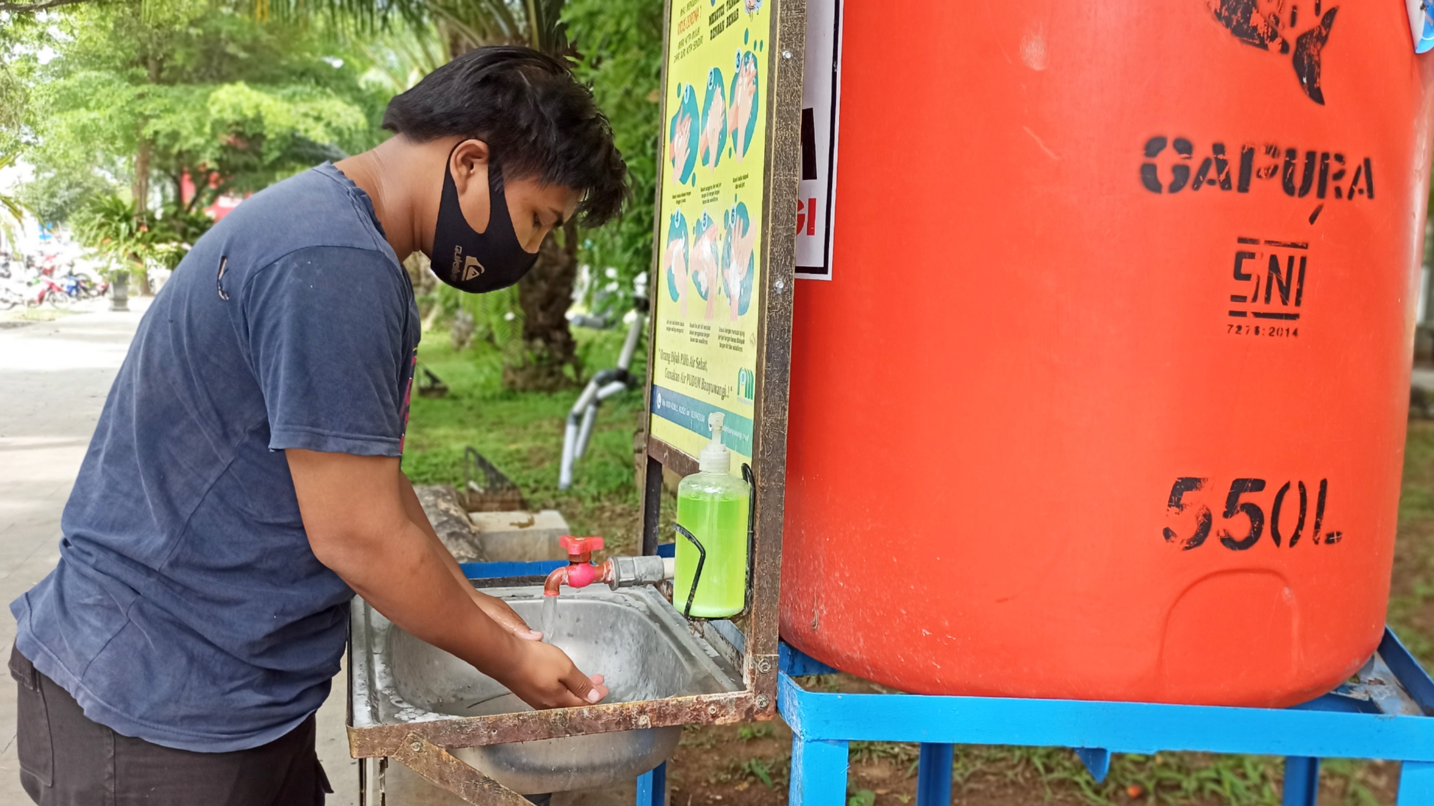 Rahmat Dani, pengunjung Taman Sayu Wiwit sedang mencuci tangan di area yang disediakan. (Foto: Muh Hujaini/Ngopibareng.id)
