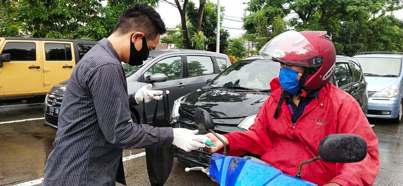 Daniel Lukas Rorong (Humas PDOI Jatim) saat membagikan masker dan hand sanitizer pada masyarakat, termasuk ojol dan pengendara motor yang melintas. (Foto: Istimewa)