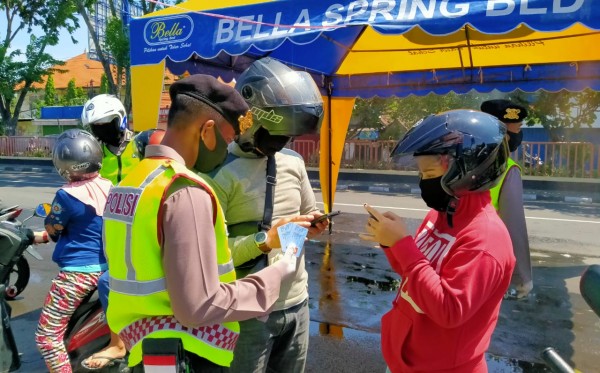 Anggota Kepolisian memeriksa identitas pengendara yang melanggar aturan PSBB di cek poin Waru, Sidoarjo, Jumat 1 Mei 2020. (Foto: Fariz Yarbo/Ngopibareng.id)