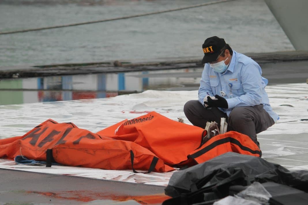 Seorang petugas  di depan kantong Jenazah yang baru diturunkan dari kapal di Dermaga IJCT  Tanjung Priok. (Foto: asmanu/ngopibareng.id)