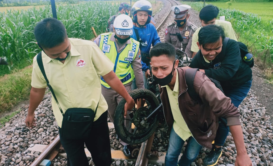Petugas bersama warga mengangkat sepeda motor korban yang terseret kereta api (Foto: istimewa)